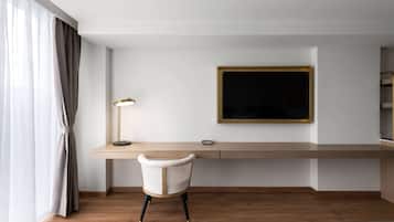 Une chambre d’hôtel avec un bureau en bois, une chaise, un téléviseur fixé au mur et un lit.