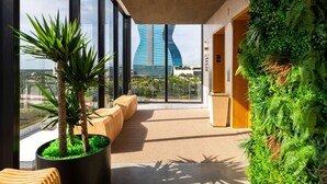 Un hall d’hôtel moderne doté de grandes fenêtres, d’un espace salon et d’un jardin vertical.