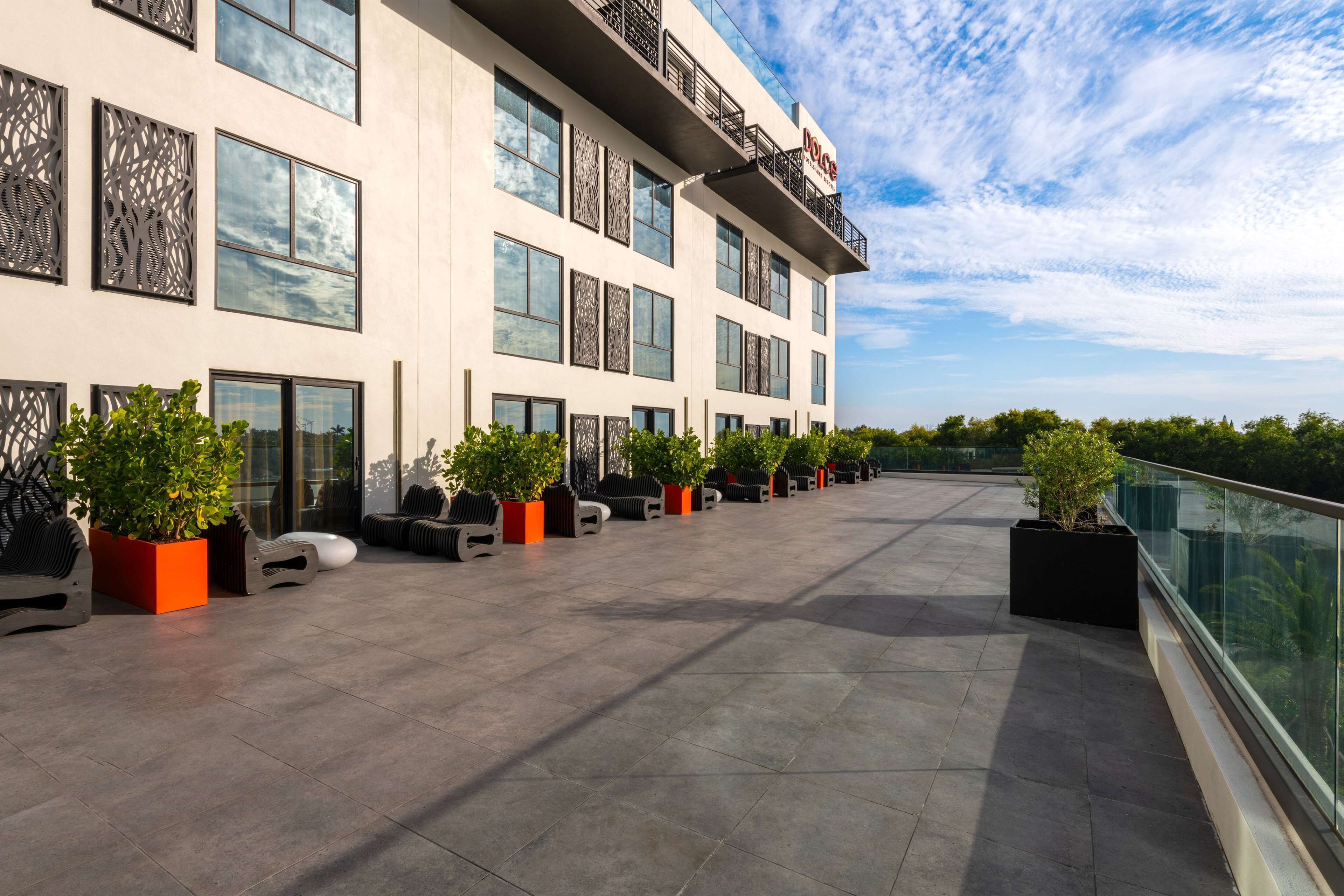 Et moderne hotel med en rummelig udendørs terrasse, store vinduer og en klar himmel.