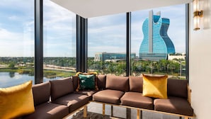 Un intérieur moderne avec un canapé d’angle, de grandes fenêtres et une vue sur un bâtiment remarquable.