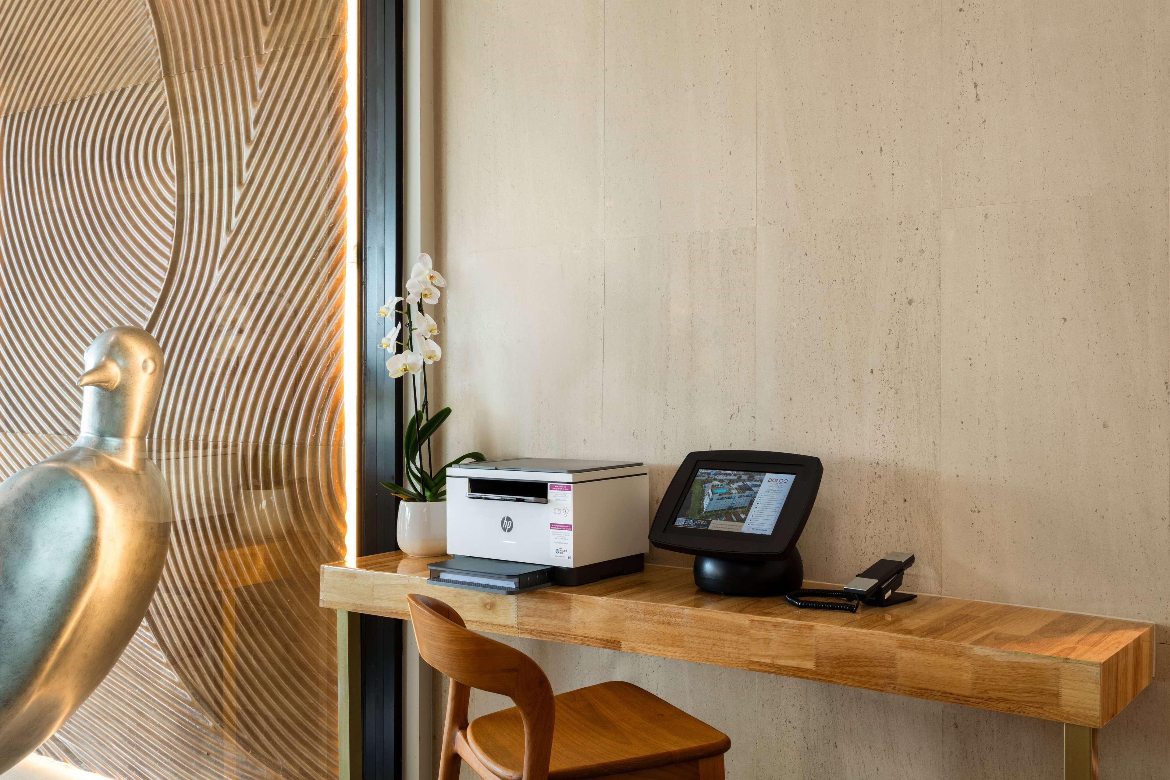 Un escritorio de madera con una impresora, un monitor y una planta.