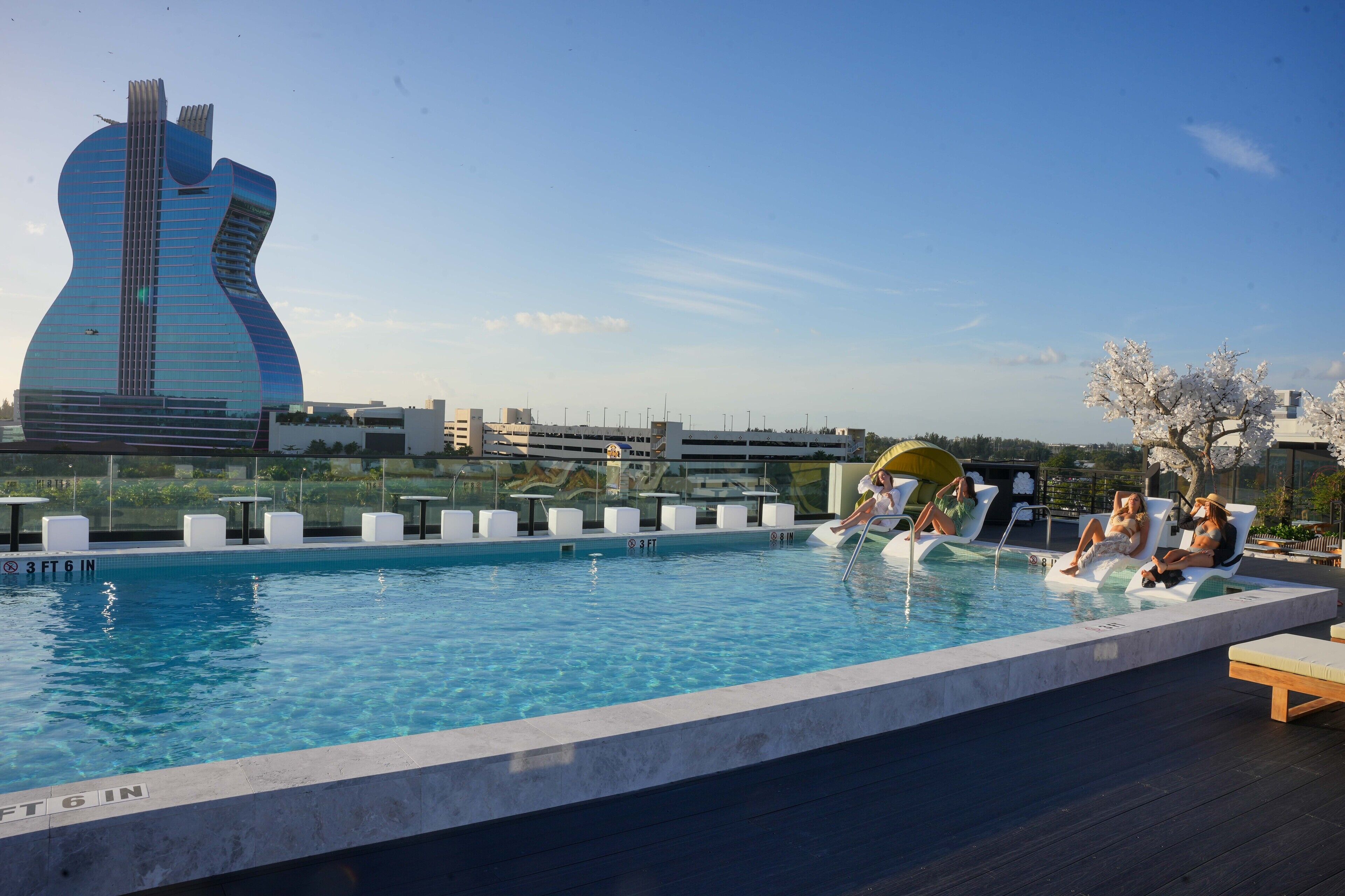 A pool area with lounge chairs and a unique building in the background.