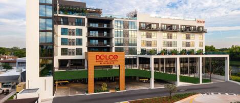 A modern hotel with multiple floors, a prominent sign, and a landscaped entrance area.