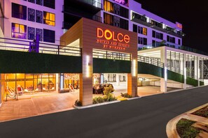 A hotel with a prominent 'Dolce Hotels and Resorts' sign, a covered entrance, and a parking area.