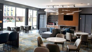 Un lobby moderno de hotel con áreas de estar, una chimenea y una gran pantalla de televisión.