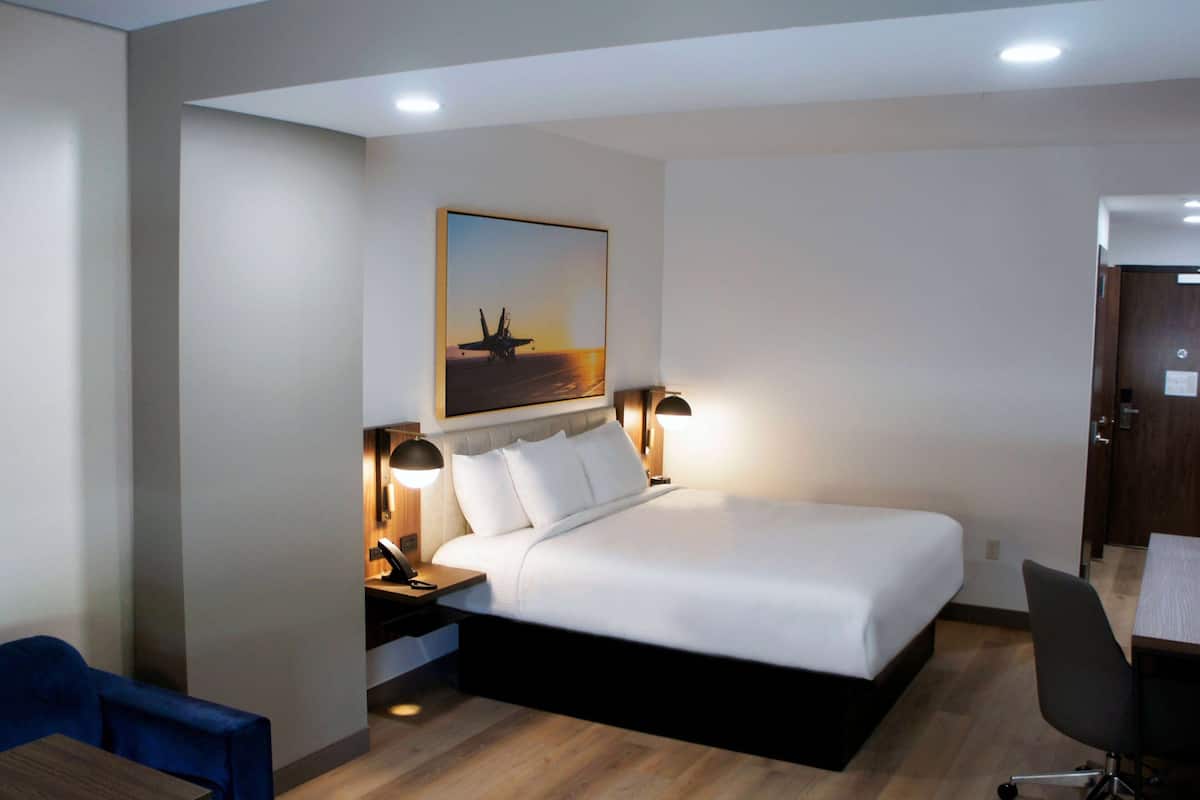 Ein Hotelzimmer mit Bett, Nachttischlampen, Schreibtisch und Stuhl.