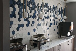 A modern kitchen with a white countertop, stainless steel appliances, and a hexagonal tile backsplash.