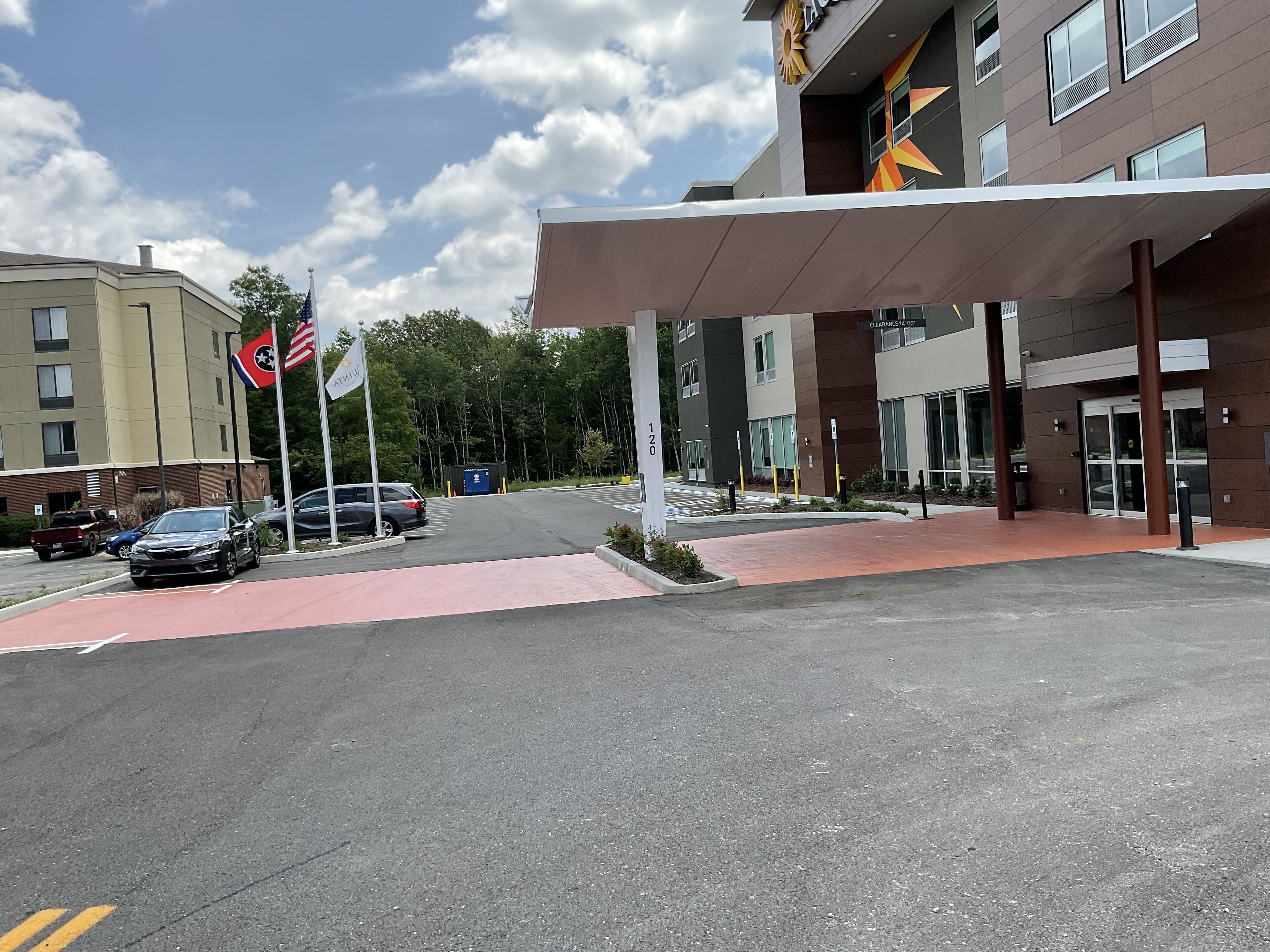 A parking lot with cars, a building entrance, and a flag.