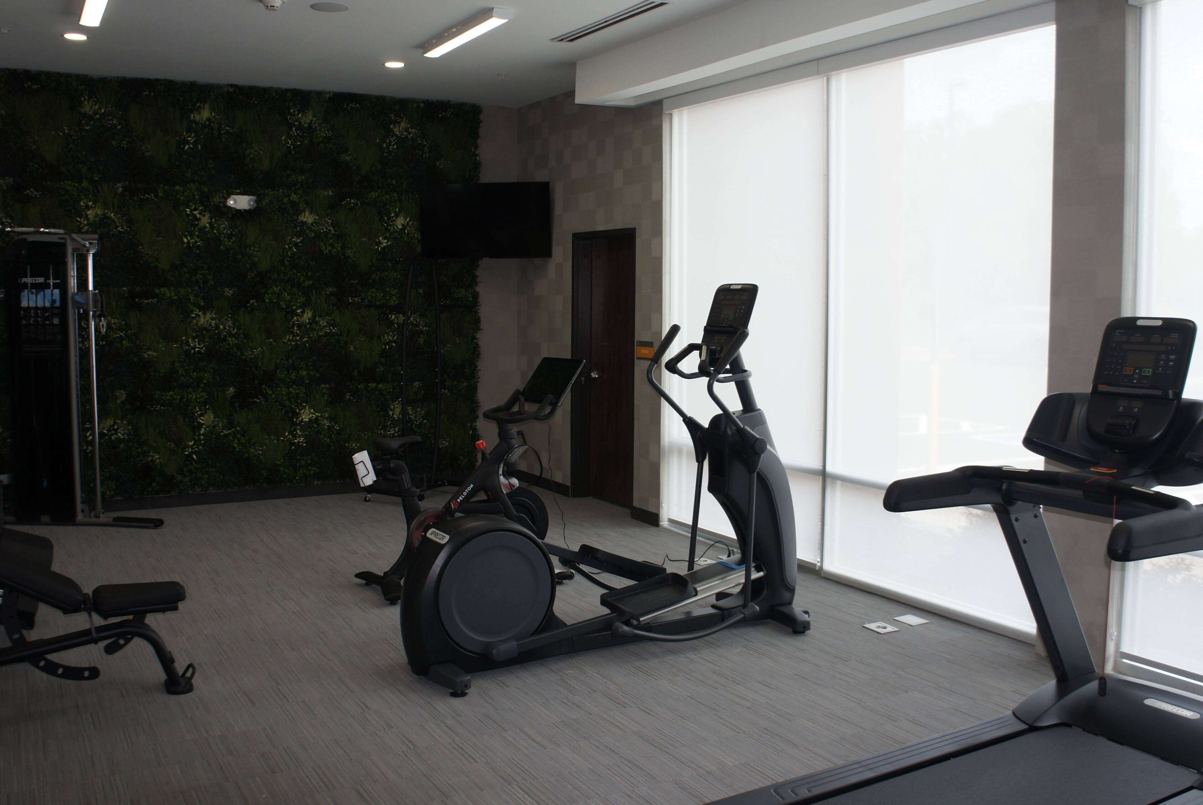 Un gimnasio con bicicletas estáticas, cintas de correr y una banca.