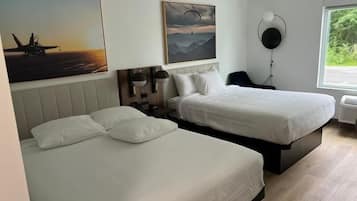 Et hotelværelse med to senge, et stort vindue med udsigt til grøn vegetation og kunst på væggene.