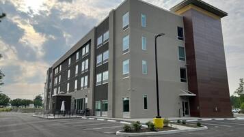 A multi-story building with a flat roof, large windows, and a parking lot in front.