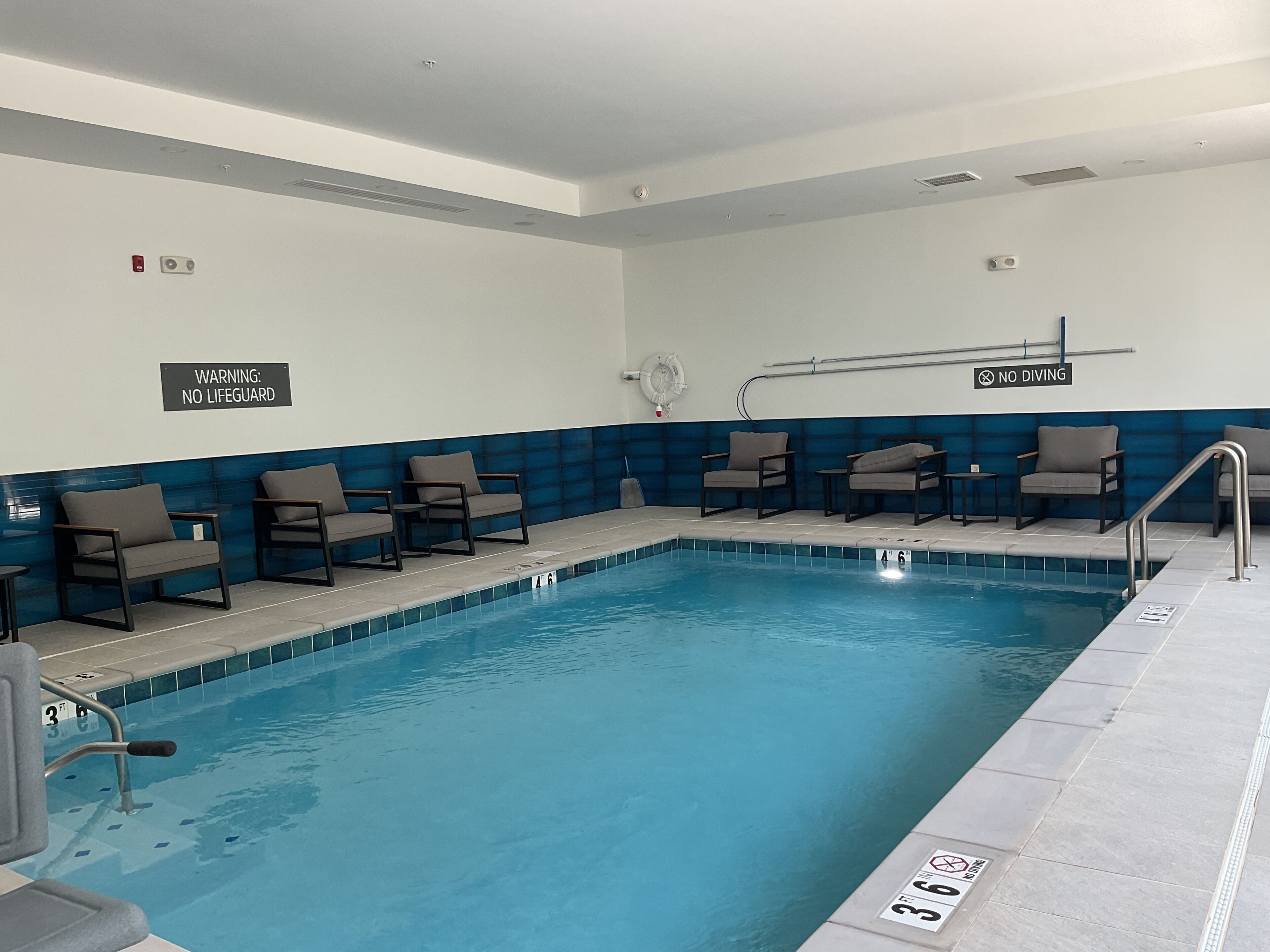 An indoor pool with lounge chairs and a 'No Diving' sign.