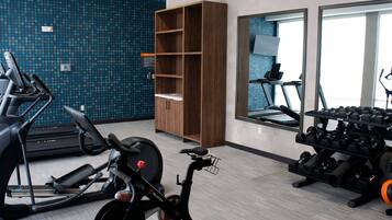 A gym with exercise equipment, a mirrored wall, and a blue patterned wall.