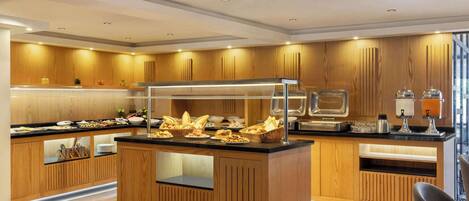 A modern kitchen with wooden cabinetry, a central island with a glass enclosure, and a buffet setup.