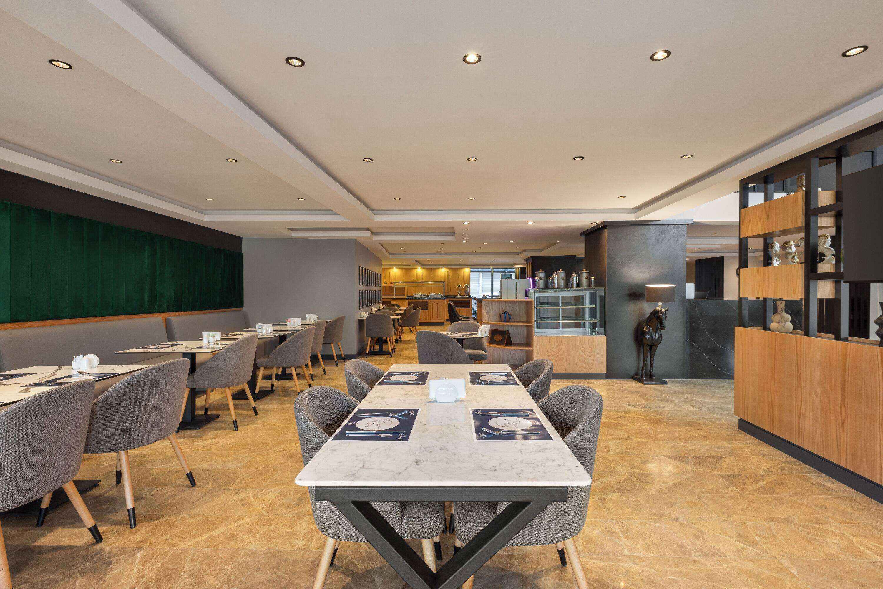 Un restaurante moderno con una larga mesa de comedor, múltiples sillas y una zona de bar con estantes.