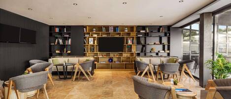 A modern living room with a flat-screen TV, multiple bookshelves, and comfortable seating.
