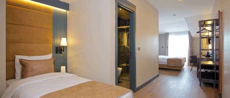 A hotel room with a large bed, a walk-in closet, a desk with a chair, and a bathroom with a toilet and shower.