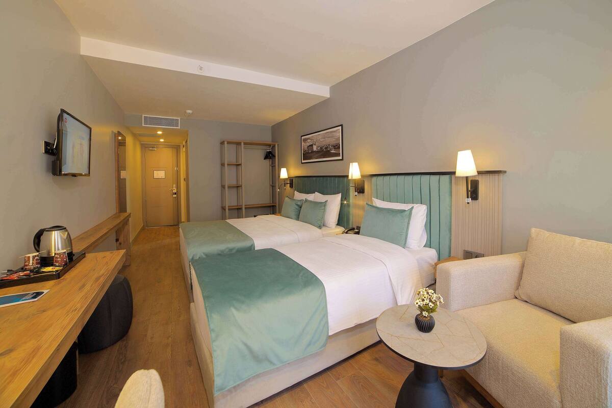 Una habitación de hotel con cama, sofá, una mesita, escritorio y televisión.
