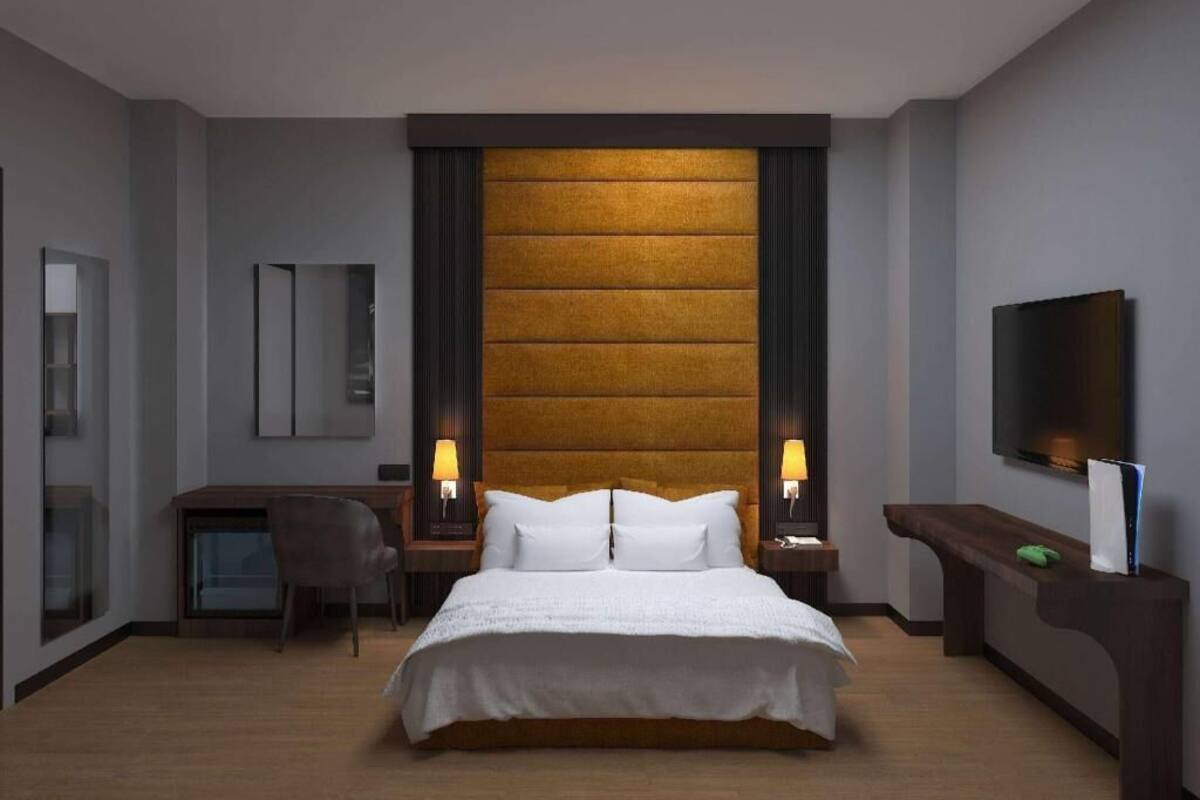Una habitación de hotel con una cama grande, un escritorio, una silla, un televisor y un espejo.