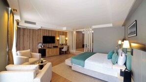 Una habitación de hotel moderna con cama, zona de estar, escritorio y televisión.