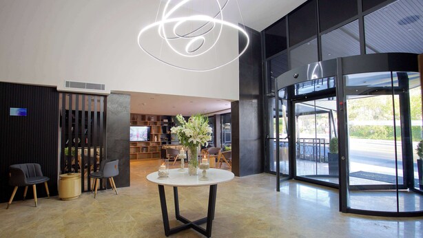 Un lobby moderno con una mesa redonda, dos sillas, un jarrón decorativo y una lámpara de techo original.