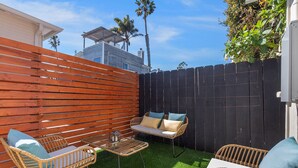 A patio with wicker furniture, a small table, and artificial grass. - Pet-Friendly OB Bungalow w/ Patio, Grill & Walk to Beach (San Diego)