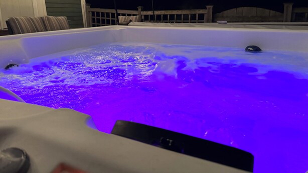 Ein Whirlpool mit blauem Licht, umgeben von einer Terrasse und Lichterketten.