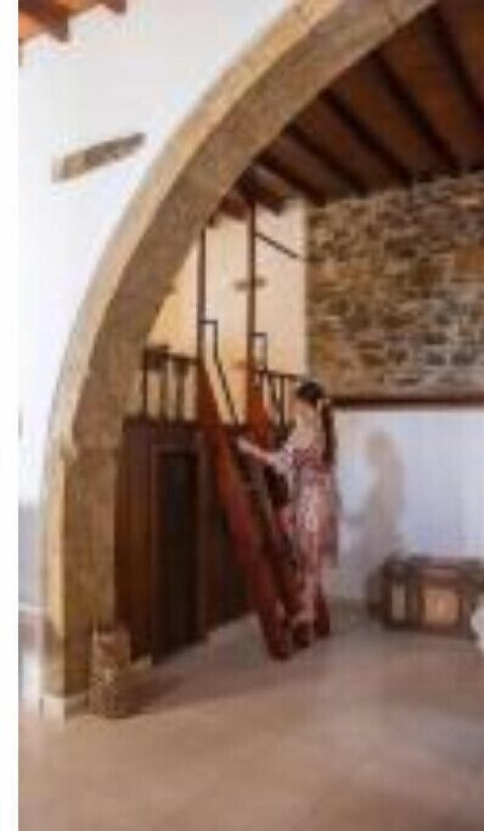 Ein rustikales Interieur mit Steinwand, Holzbalken und einer Treppe.