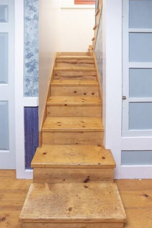 Una escalera de madera con barandilla que lleva a una puerta con paneles de vidrio esmerilado.