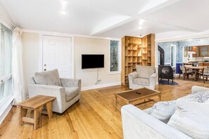 Un salón amplio con un sofá gris, una mesa de centro de madera y un televisor montado en la pared.