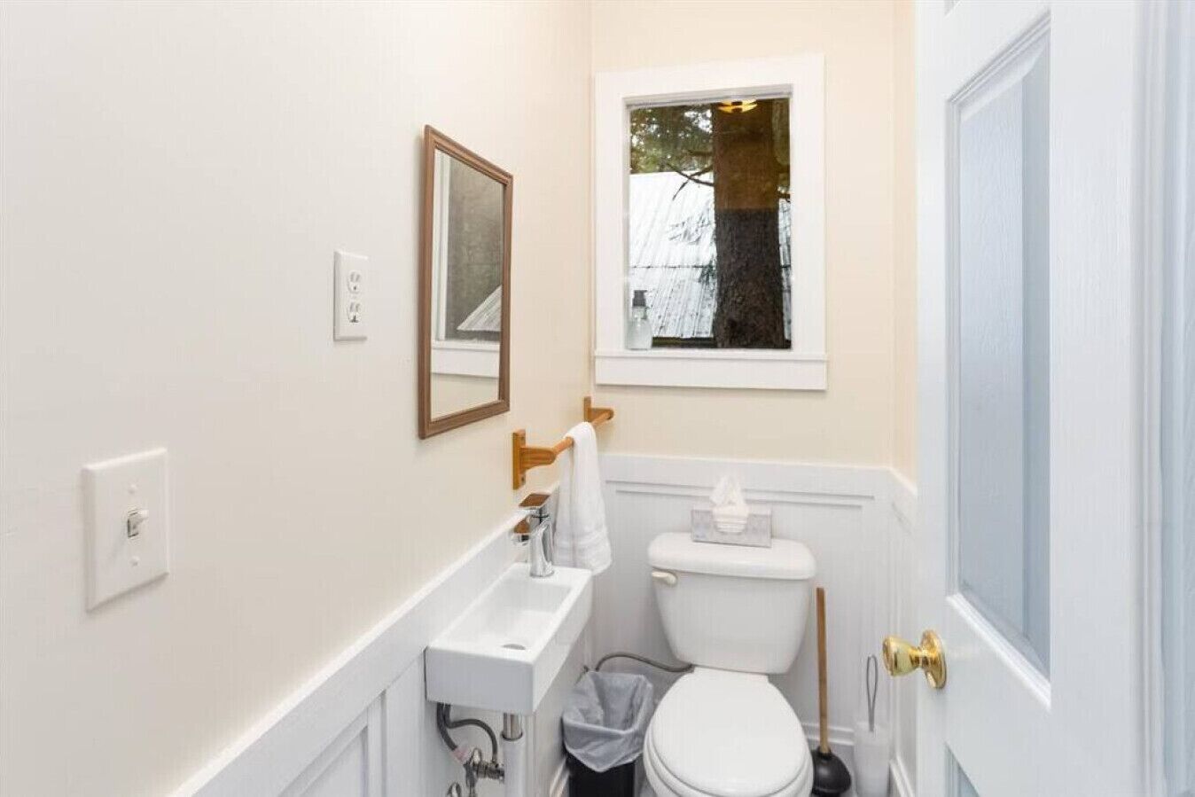 A small bathroom with a toilet, sink, and window.