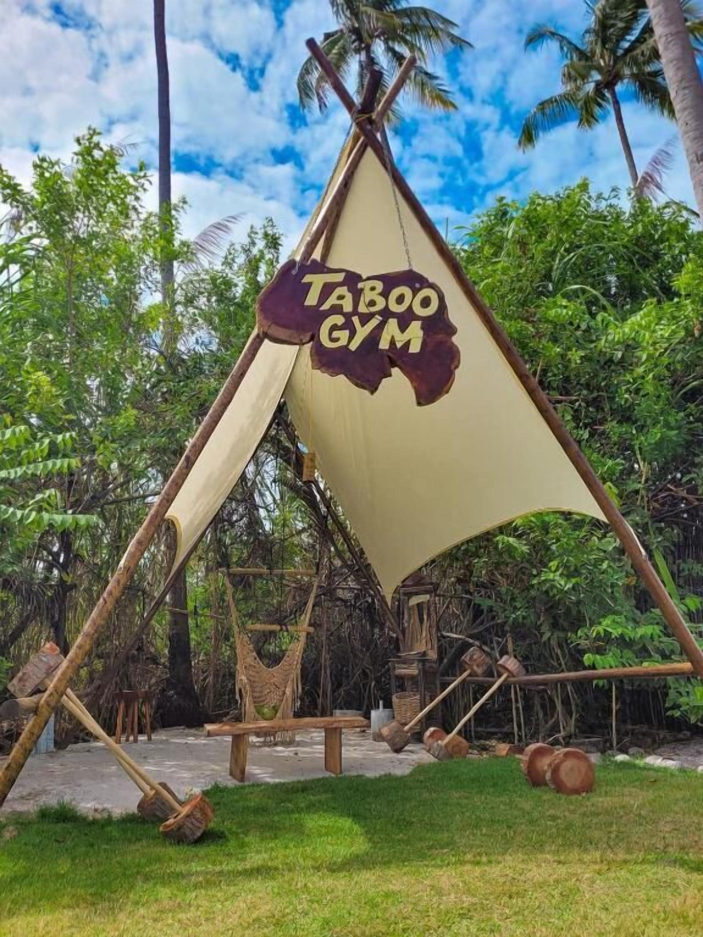 Una carpa con un letrero que dice "Taboo Gym" en un entorno tropical.
