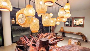 A modern interior with a large wooden sculpture centerpiece, hanging woven light fixtures, and a minimalist design. - Taboo Milagres (São Miguel dos Milagres)