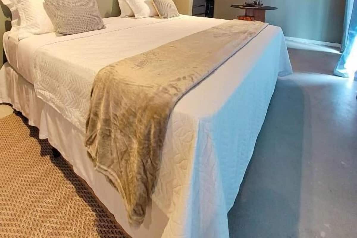 Een moderne slaapkamer met een groot bed, een houten deur en een wandairconditioner.