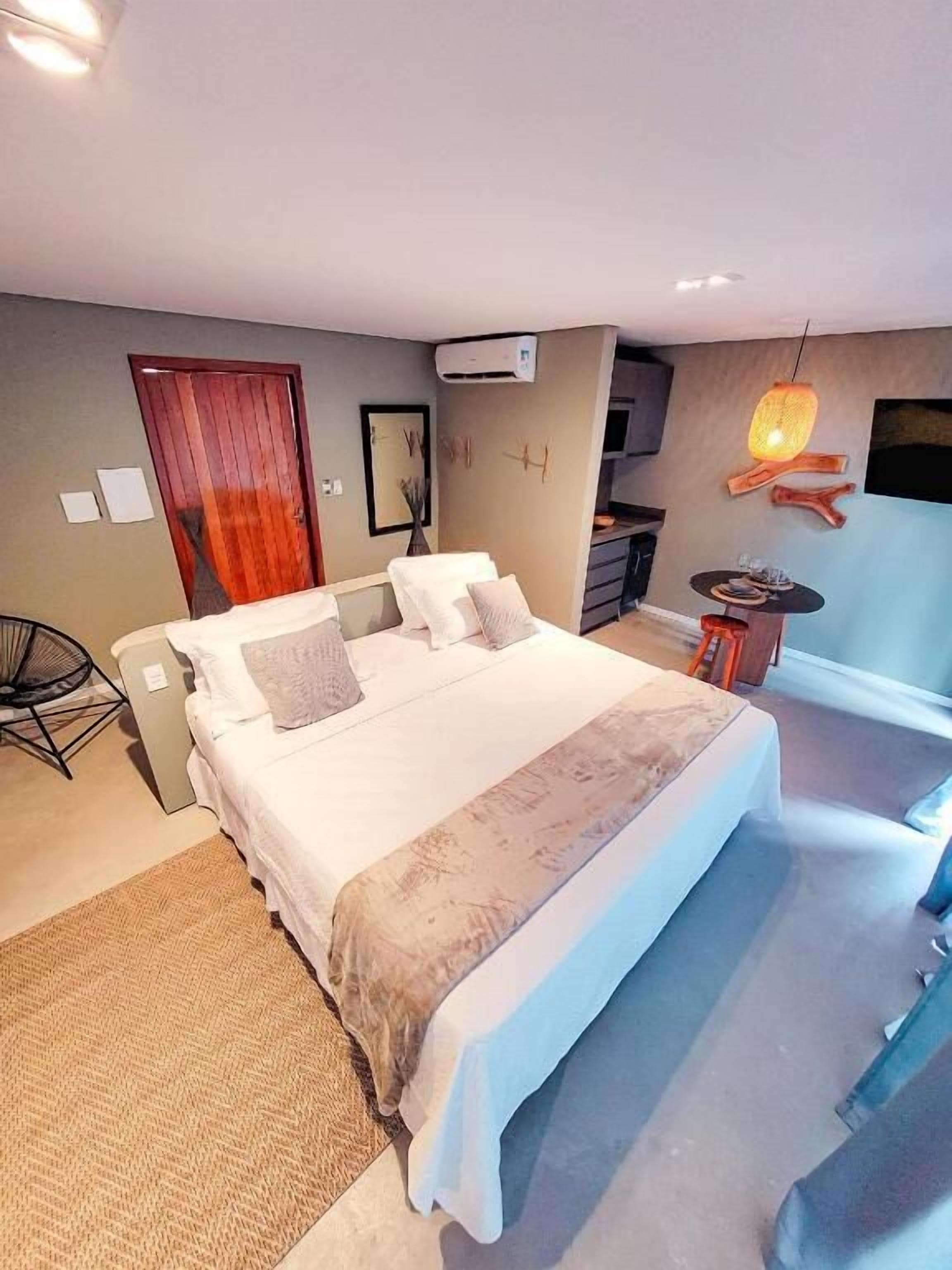 Une chambre à coucher avec un lit, une chaise, une petite table et un téléviseur.