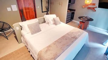 Quarto com cama, uma cadeira, uma mesinha e uma televisão.
