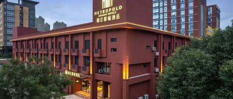A modern hotel building with a prominent sign, multiple floors, and a well-lit entrance.