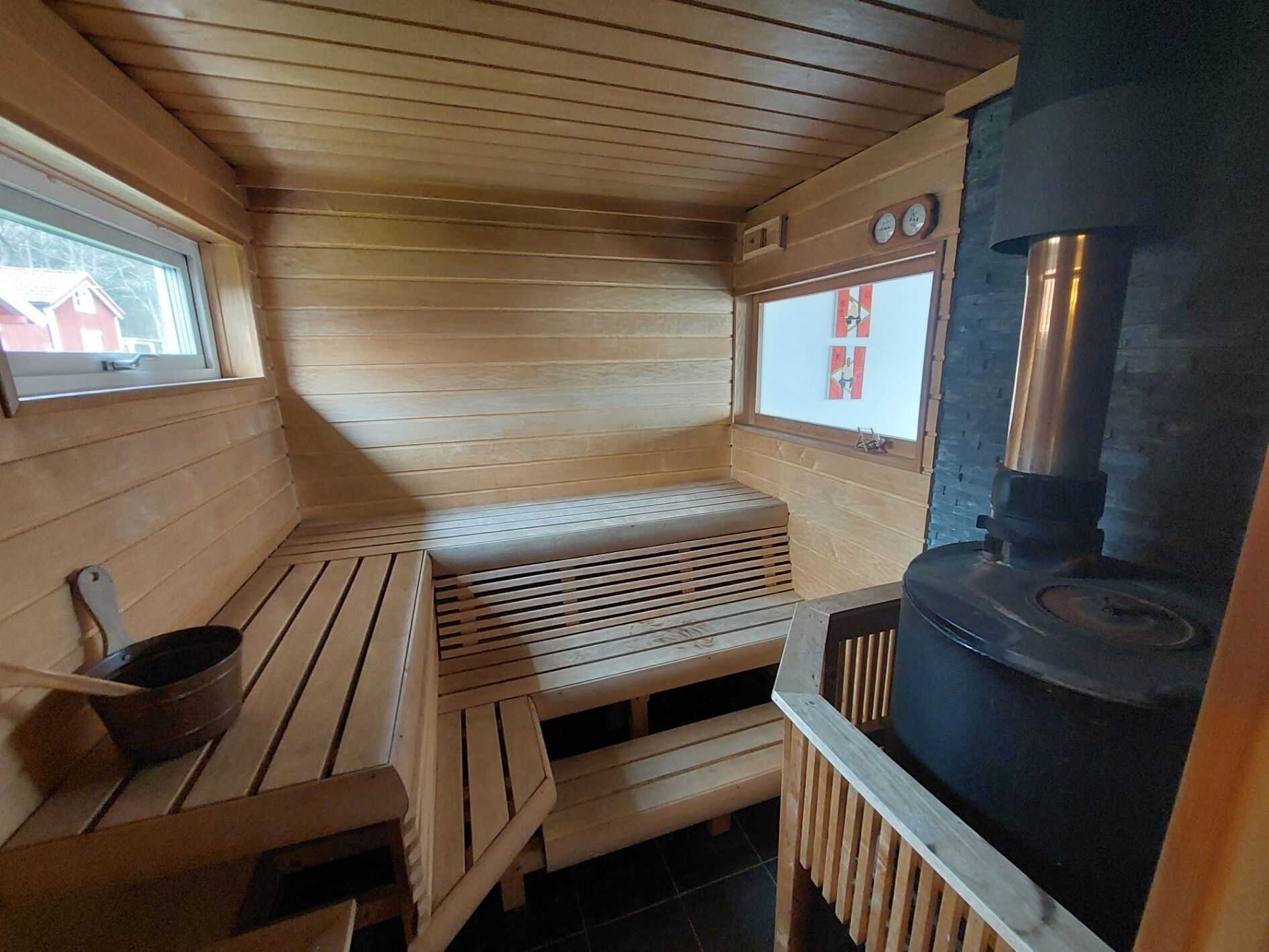 Een sauna met houten banken, een zitbank, een raam en een sauna-oven.