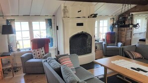 Een gezellige woonkamer met een open haard, grijze banken, een houten salontafel en een raam met gordijnen.