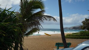 A beach with a lifeguard stand, palm trees, and a bench. - Hawaiian Hale  (Hauula)