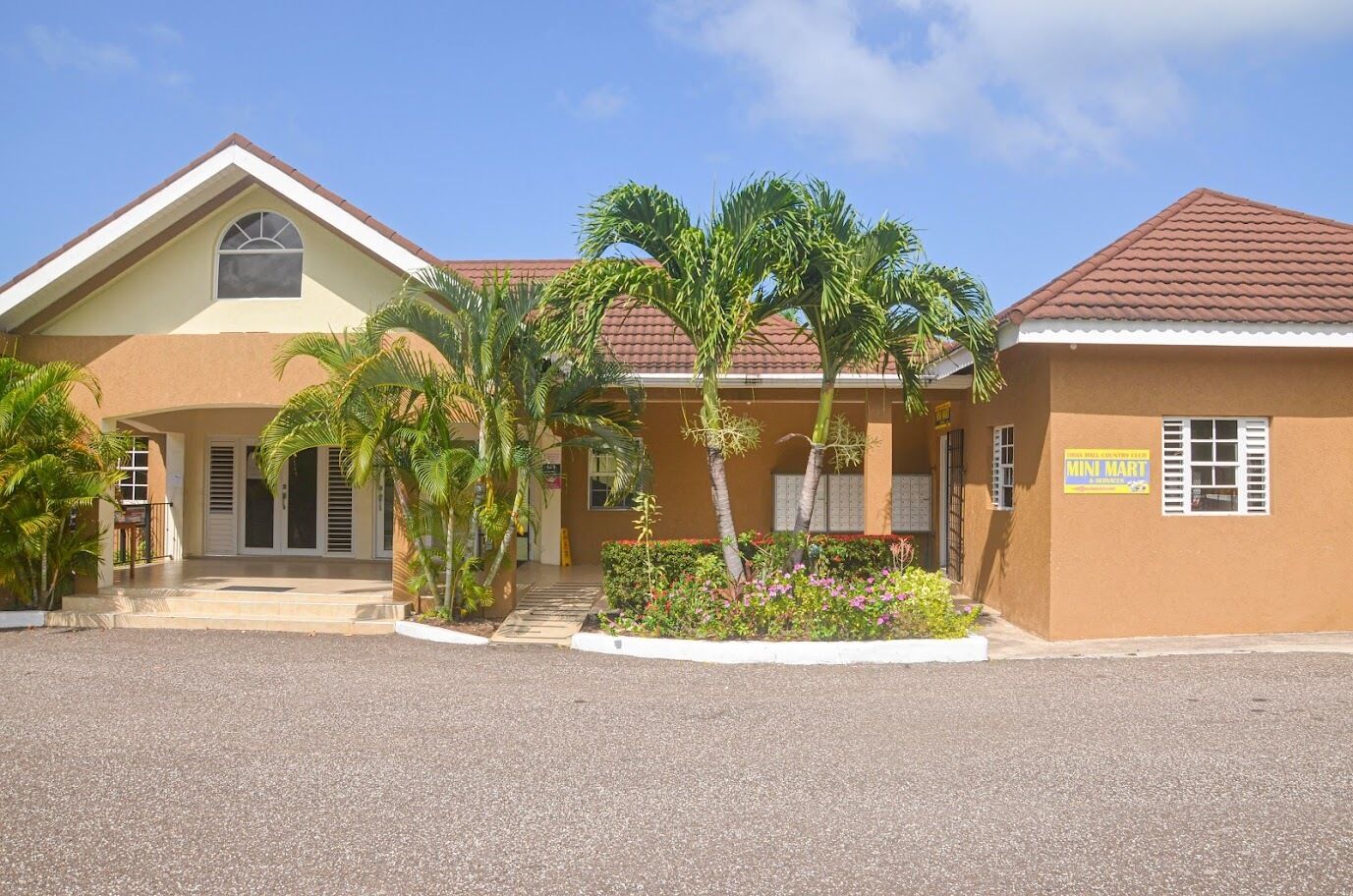 A two-story building with a brown facade, a tiled roof, and a sign for a mini mart.