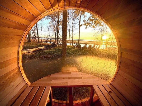Una estructura circular de madera con vista a un lago y árboles.