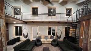 Een ruime woonkamer met zwarte banken, een salontafel en hangende hangmatten.