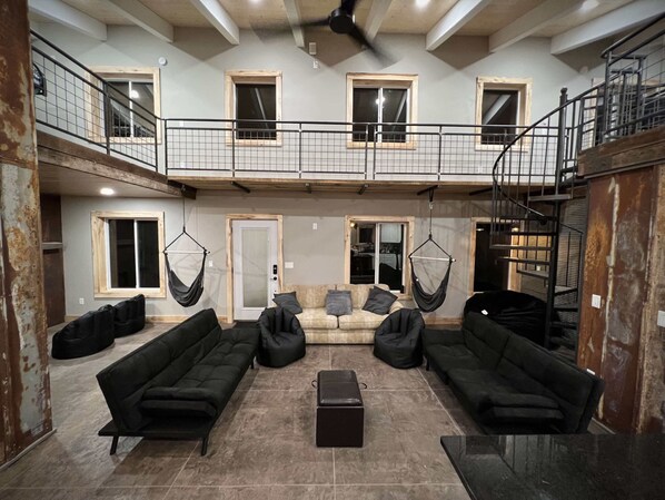 Ein großzügiger Wohnbereich mit schwarzen Sofas, einem Couchtisch und Hängematten.