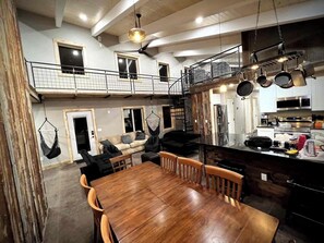 Un espace de vie à plusieurs niveaux comprenant un coin repas, une cuisine et un balcon supérieur.