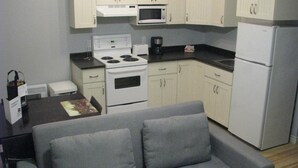 A compact kitchen with white cabinets, a microwave, a stove, and a refrigerator. - Budget loft with two beds + sofa bed (Le Citadin) (Rouyn-Noranda)