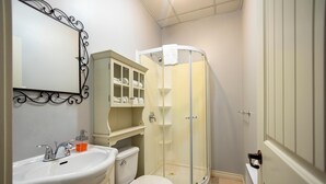 A bathroom with a white sink, toilet, and a glass-enclosed shower. - Loft Economique in the heart of Rouyn-Noranda (Le Citadin) (Rouyn-Noranda)