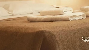 A neatly made bed with white linens and a light brown bedspread, a wall-mounted light fixture, and a partially visible headboard. - Viento Andino (San Rafael)