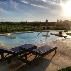 Ein Swimmingpool mit Liegestühlen und einer Laube im Hintergrund.