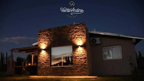 A modern house with a stone facade, a large window, and a covered outdoor area. - Viento Andino (San Rafael)
